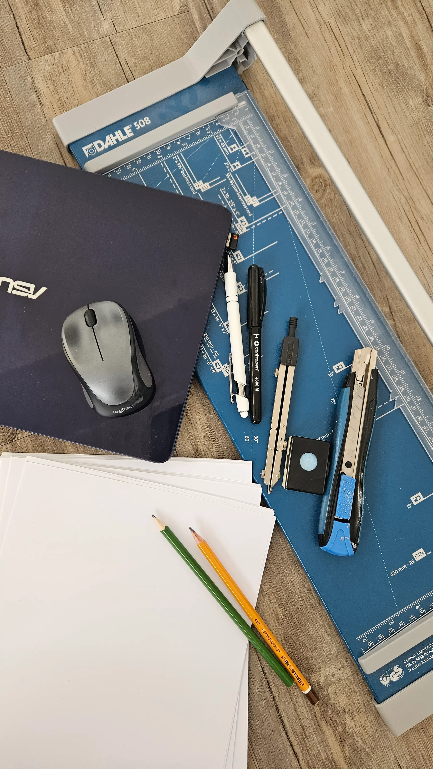 Pracovní stůl s řezačkou papíru, tužkami a notebookem